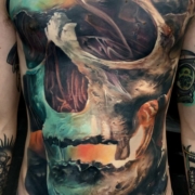 Tatuaje de una calavera con colores brillantes en el torso de un hombre