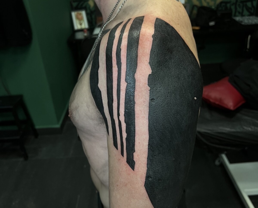 Tatuaje en el hombro de un hombre de lineas gordas negras.