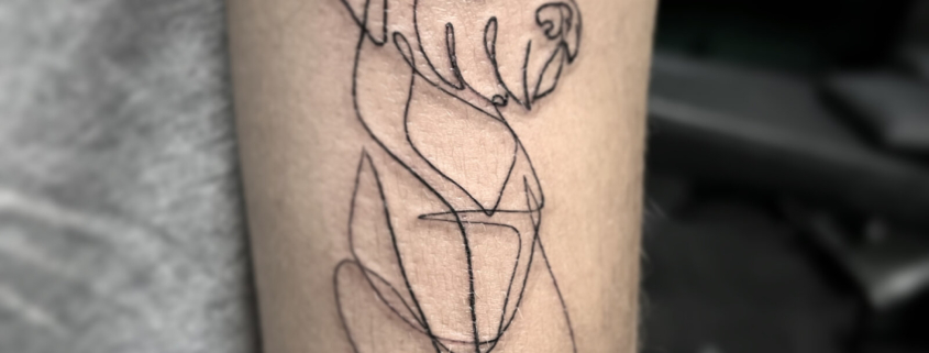Tatuaje en la zona del triceps de una mujer de un perro lineal abstracto