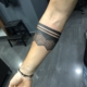 Brazalete tatuado en el antebrazo de un hombre con lineas negras y diseño ornamental con puntilismo.