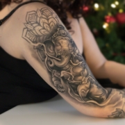 Tatuaje en el brazo de una mujer de del dios Ganesha con decoraciones de mandalas