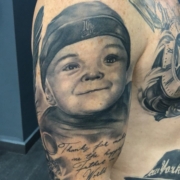 Tatuaje del retrato de un niño en el hombro de un hombre.