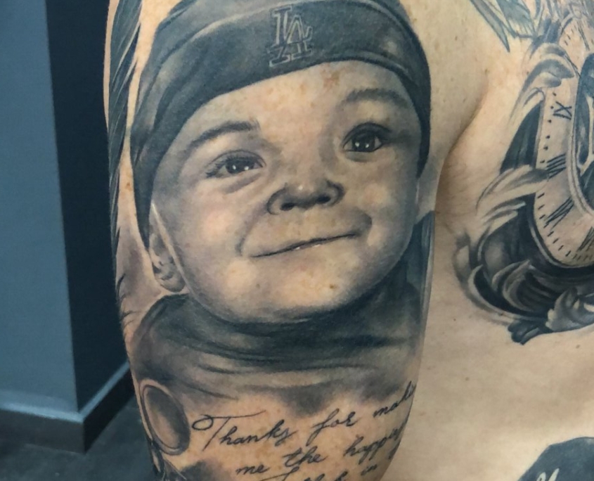 Tatuaje del retrato de un niño en el hombro de un hombre.