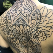 Tatuaje de diseño ornamental y floral en estilo oriental, mandala. En la espalda de una mujer.