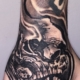 Tatuaje en la mano de un hombre de una calavera con decoracion abstracta.
