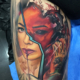 Tatuaje de un retrato de la tatuadora Valentina Riabova. El retrato es de media cara realista y la otra media cara de color rojo con el ojo negro a un estilo terror.