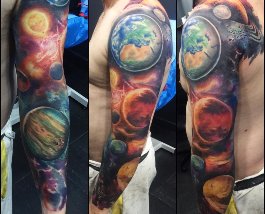 Tatuaje en el brazo de un hombre de una galaxia y planetas a color.