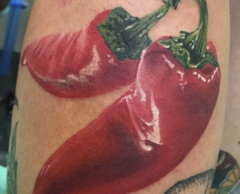 Tatuaje realista de 2 pimientos rojos en el gemelo