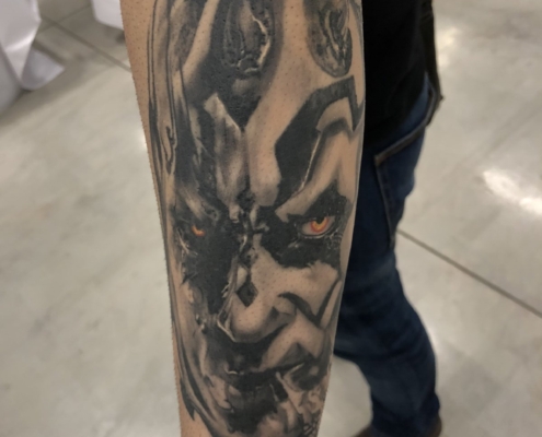 Tatuaje del personaje Darth Maul en negro y grises con los ojos a color en el antebrazo de un hombre.