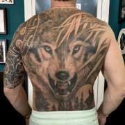 Tatuaje grande en la espalda de un hombre de un lobo realista.