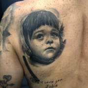 Tatuaje de un niño en el hombro en realismo en negro y grises.