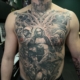 Tatuaje en el torso de un hombro con angeles y demonios representando el bien y el mal.