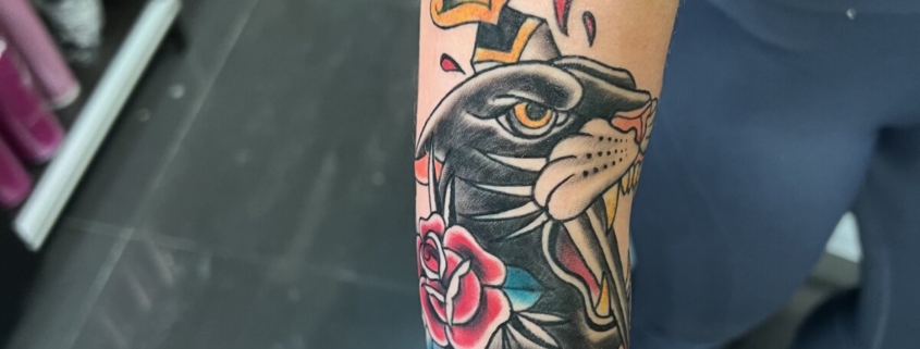 Tatuaje de una pantera con una daga en la cabeza, decorado con una rosa.