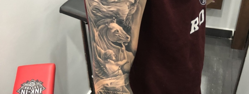 Brazo de hombre tatuado en estilo realista negro y grises con una tematica de dioses Griegos.