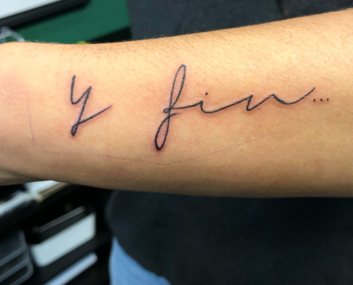 Tatuaje en linea fina de la frase: Y fin...